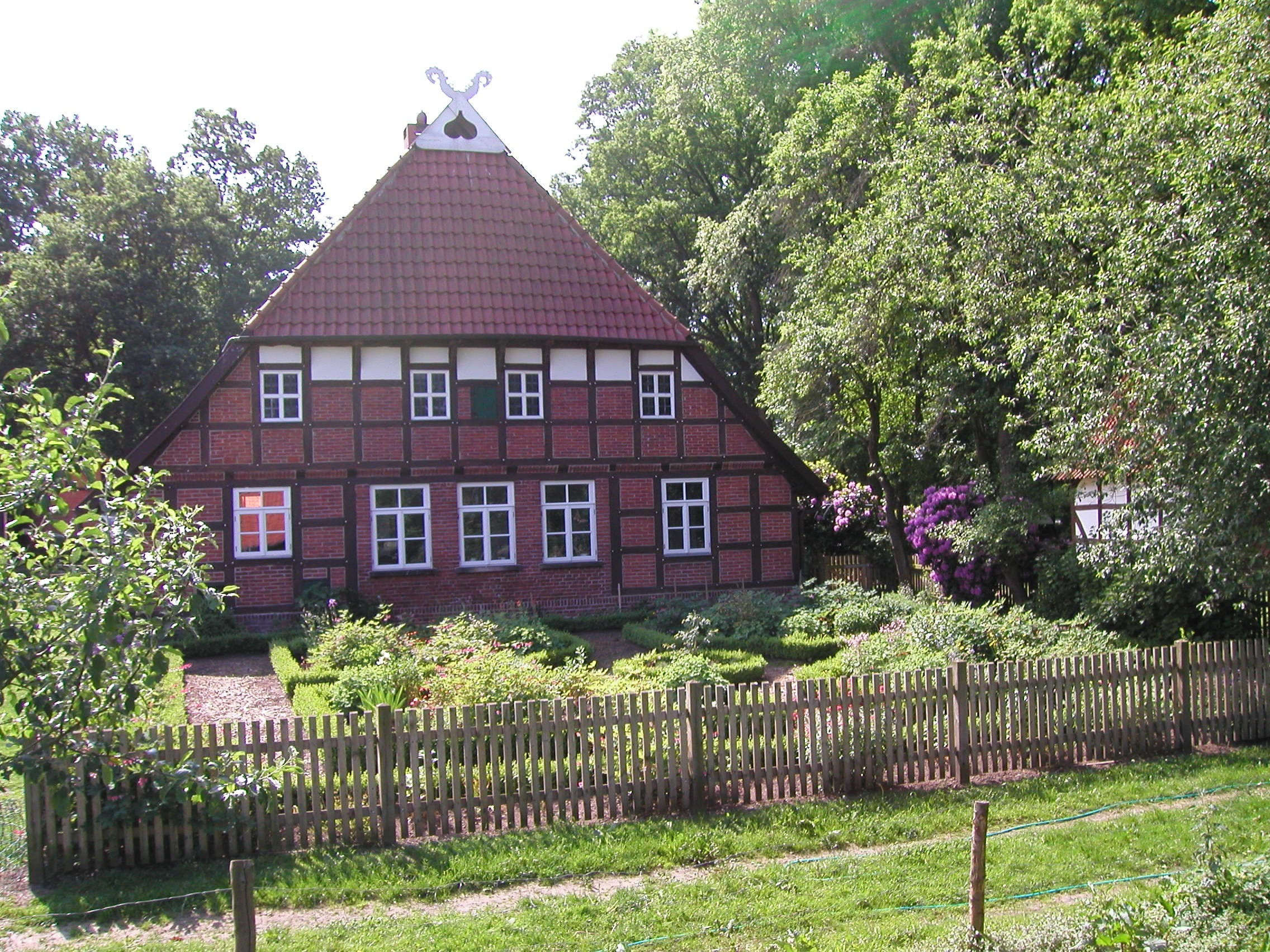 Ein altes rotes Fachwerkhaus mit Bauerngarten im Vordergrund.