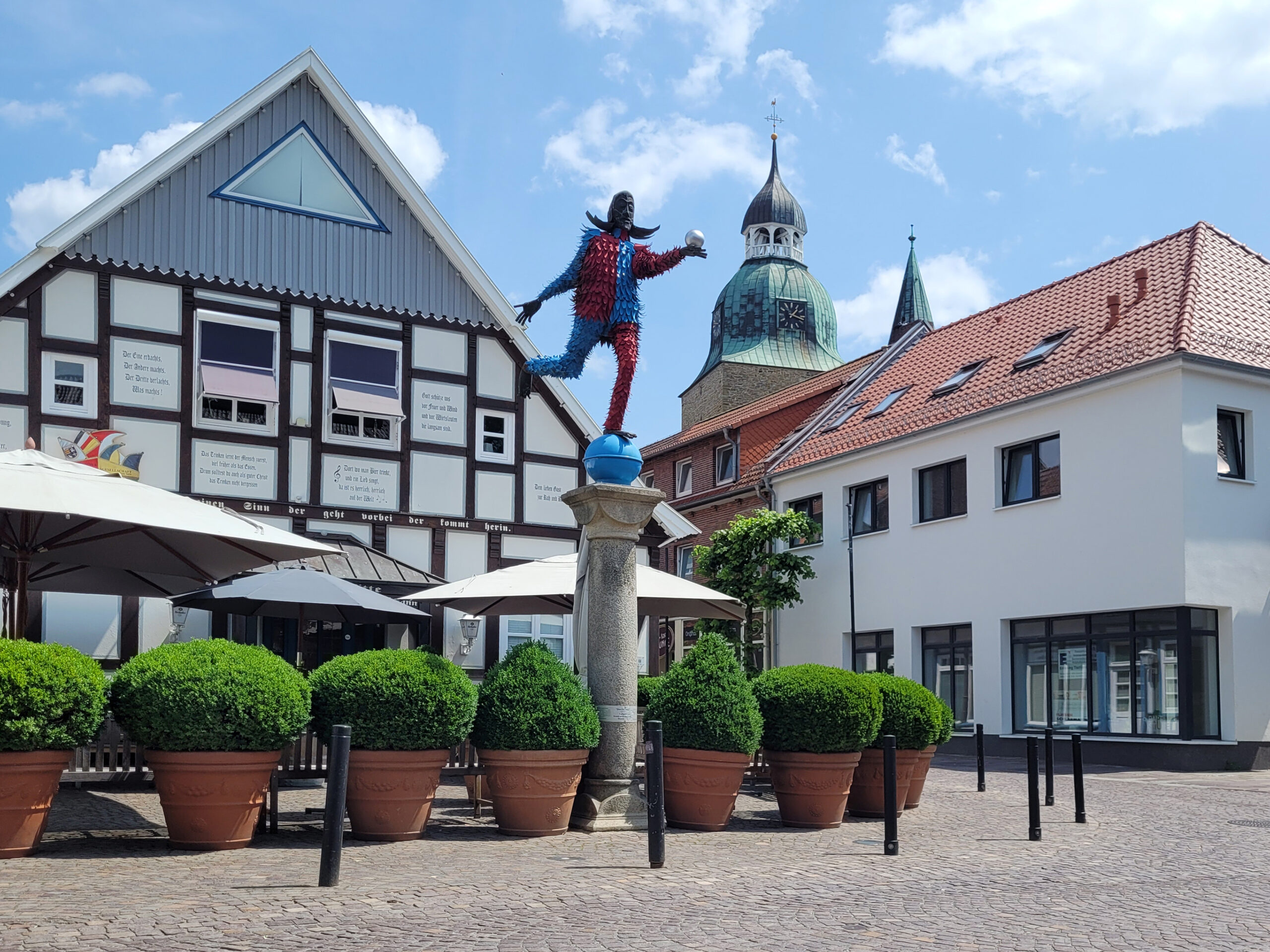 Die Statue Dammer Narr steht vor einem weißen Fachwerkhaus